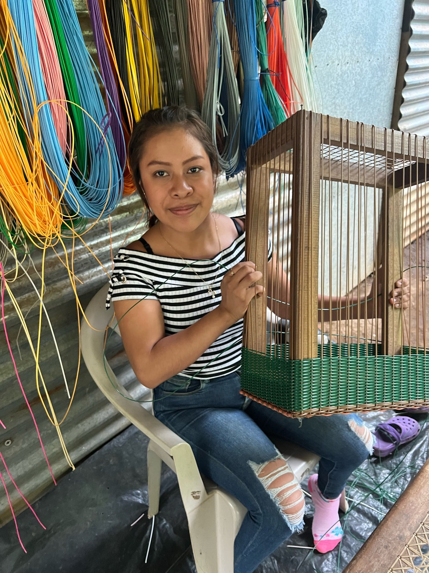 A woman is holding a basket mold that looks like a cage made from wood and strings.