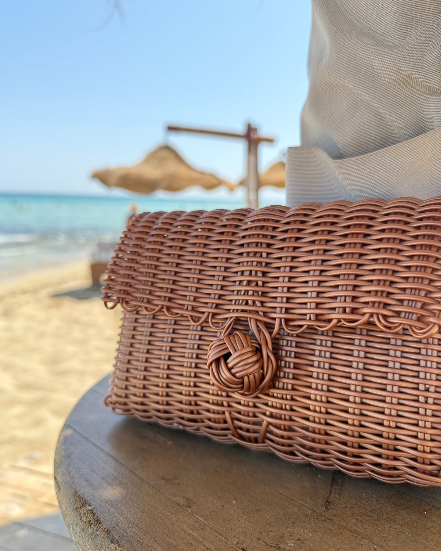 Woven clutch bag on a table with a beach background