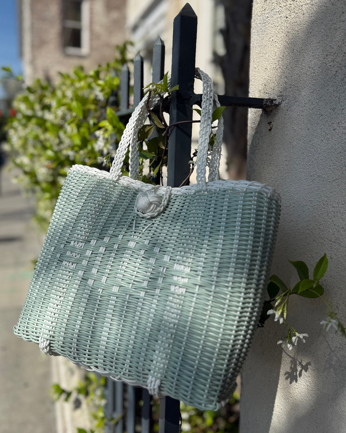 Hand-woven handbag hanging on a Charleston fence with jasmine