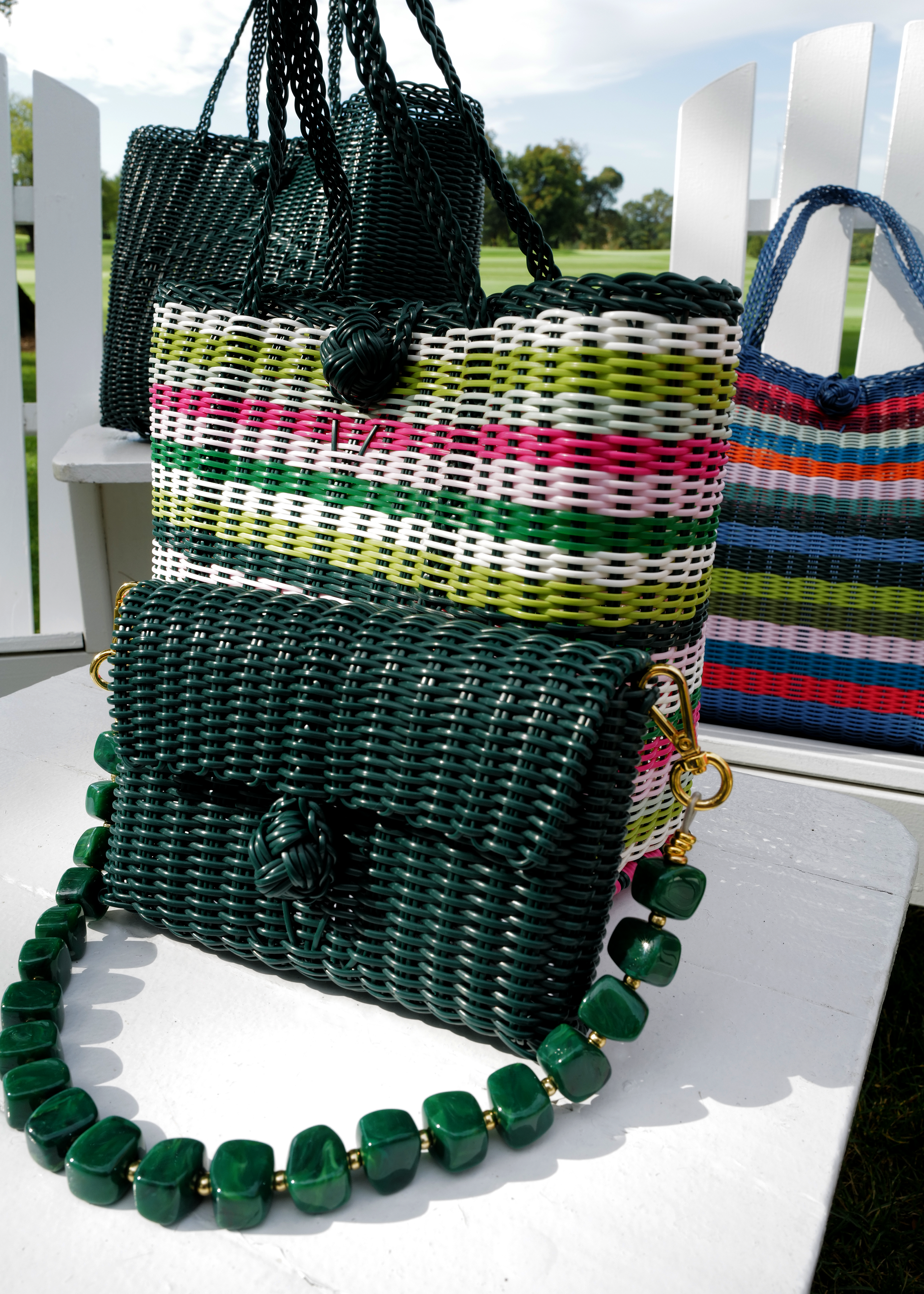 Woven handbags with colorful straps on a white surface