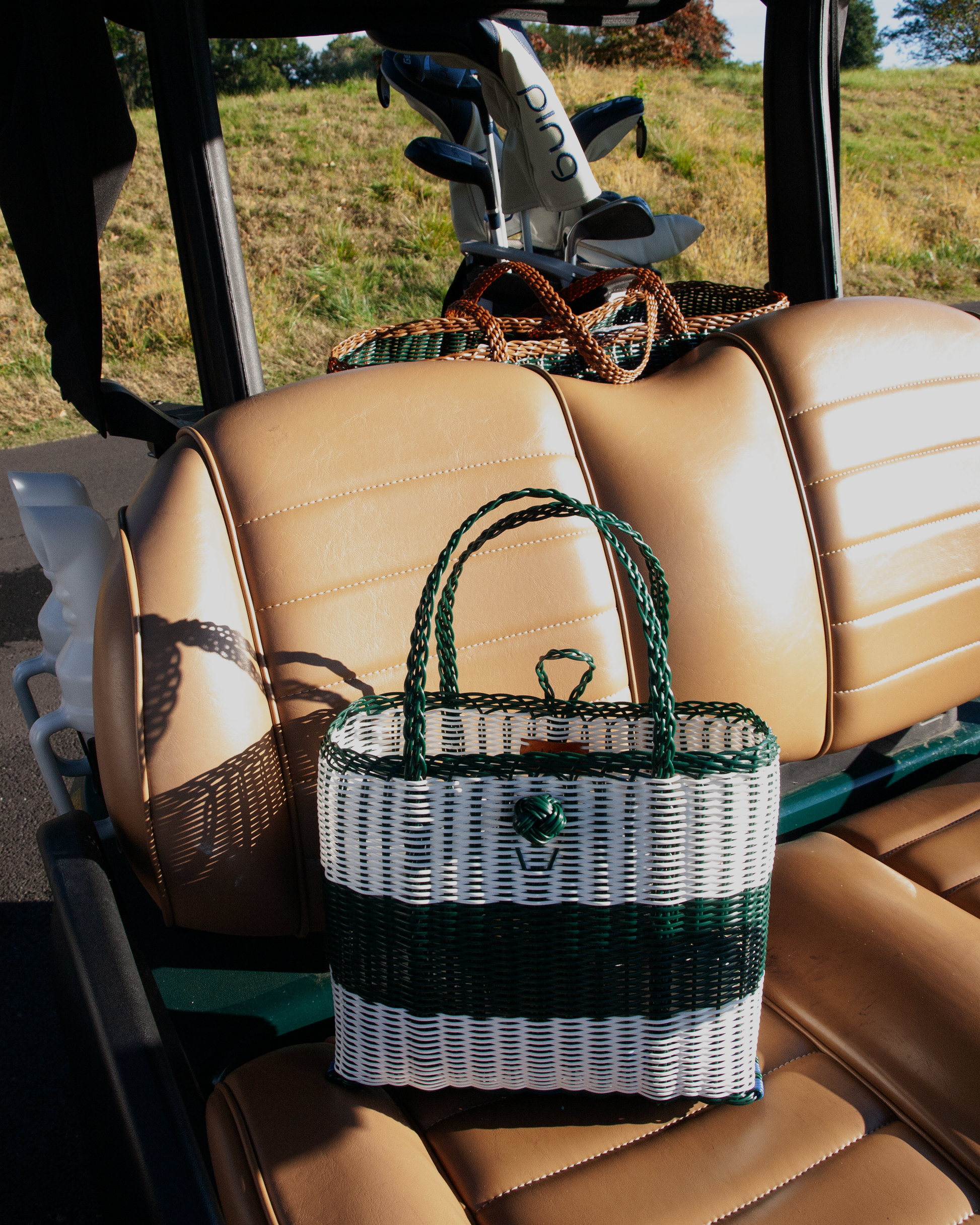Woven bag with green handles on a vehicle seat